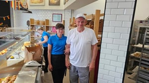 Günter Penzkofer, Inhaber einer deutschen Bäckerei in Málaga, steht mit einer Mitarbeiterin im weißen Bäckerei-Outfit in seinem Geschäft.